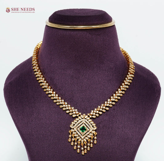 Gold-plated diamond pendant necklace featuring an emerald green center stone, sparkling American diamonds, and elegant tassel drop design.|She Needs Jewellery

