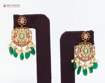 Pair of royal gold temple drop earrings featuring American Diamond stones, green bead drops, pink stone accents, and pearl detailing.|She Needs Jewellery
