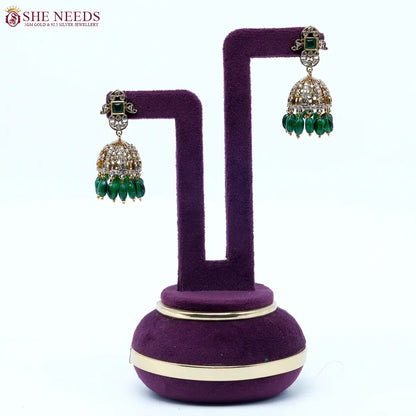 Gold-tone dome jhumka earrings featuring sparkling white stones, emerald green square stud accents, and dark green bead drops in a traditional ethnic design.|She Needs Jewellery
