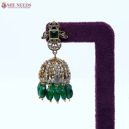 Gold-tone dome jhumka earrings featuring sparkling white stones, emerald green square stud accents, and dark green bead drops in a traditional ethnic design.|She Needs Jewellery
