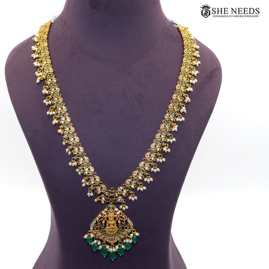 Long gold-toned Lakshmi necklace featuring intricate temple motifs, emerald green stones, ruby accents, white stones and pearl drops|She Needs Jewellery
