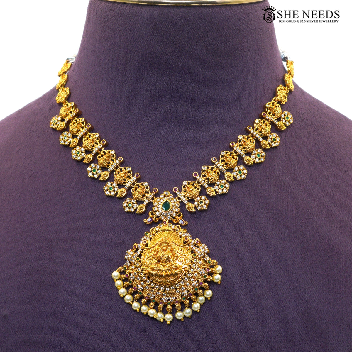 Close-up of ornate Lakshmi pendant with ruby and green stone detailing and pearl drops|She Needs Jewellery
