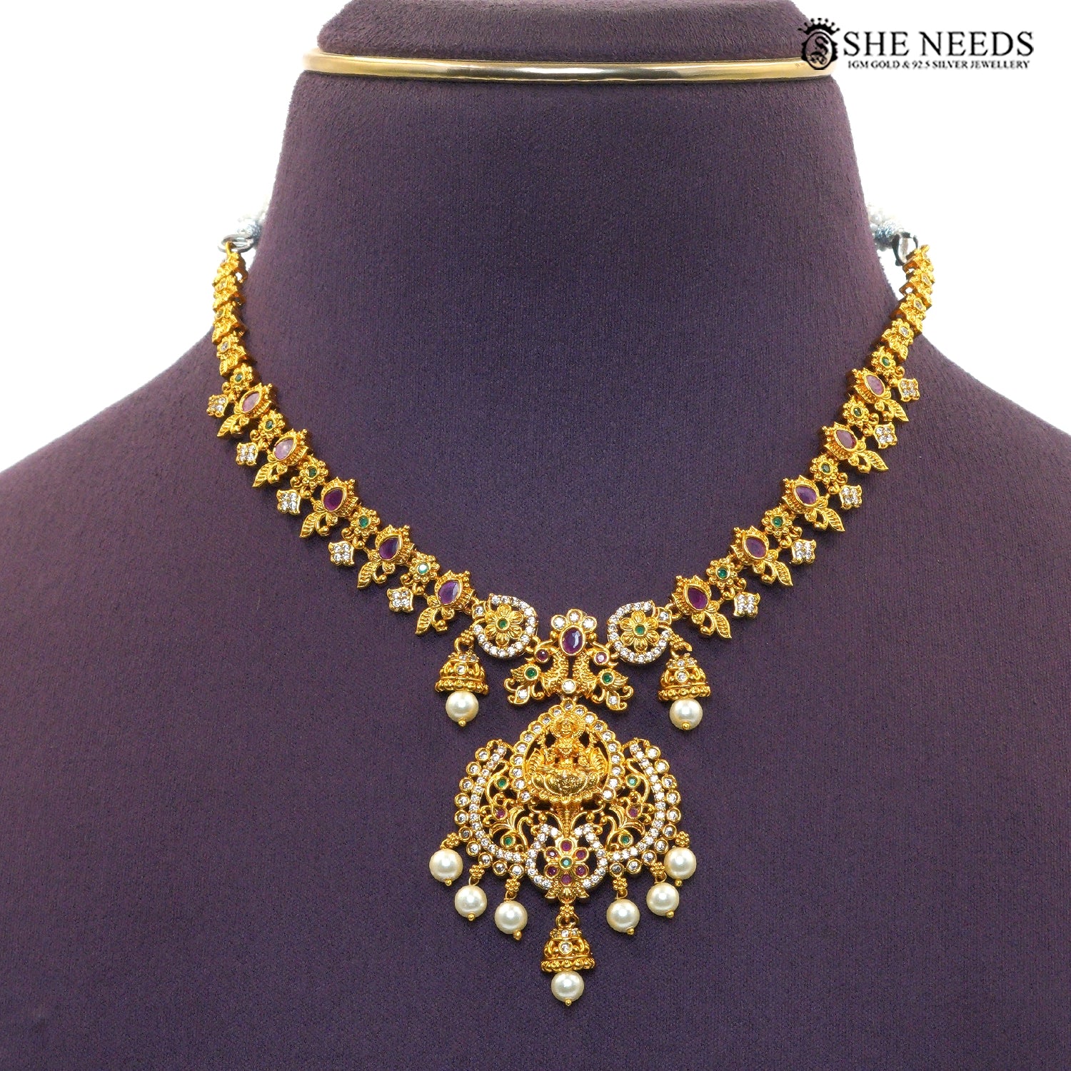Close-up of ornate Lakshmi necklace pendant with ruby stones, green accents and pearl drops|She Needs Jewellery
