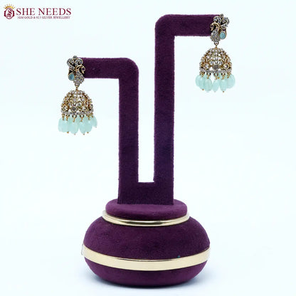Antique gold jhumka earrings featuring crystal-studded peacock motifs, sparkling CZ stones, intricate dome detailing, and elegant light green bead drops.|She Needs Jewellery