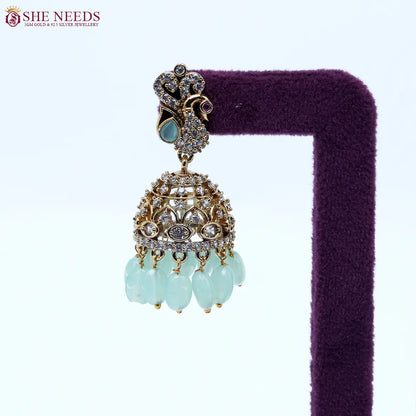Antique gold jhumka earrings featuring crystal-studded peacock motifs, sparkling CZ stones, intricate dome detailing, and elegant light green bead drops. |She Needs Jewellery