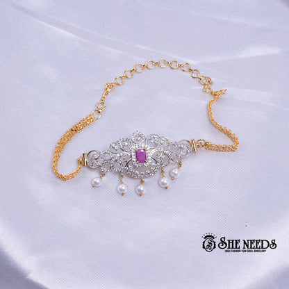 Dual-tone Royal Pearl Stone Baju Band Set featuring sparkling CZ stones, a ruby-pink center stone, intricate floral filigree detailing, and elegant pearl drop accents with an adjustable chain.|She Needs Jewellery
