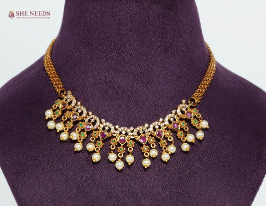 Close-up of a gold-plated royal ruby pearl fringe necklace featuring American Diamonds, emerald accents, and pearl drop detailing.|She Needs Jewellery
