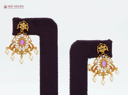Gold-plated peacock drop earrings with ruby center stone, American diamonds, green accents, and pearl drops.|She Needs Jewellery
