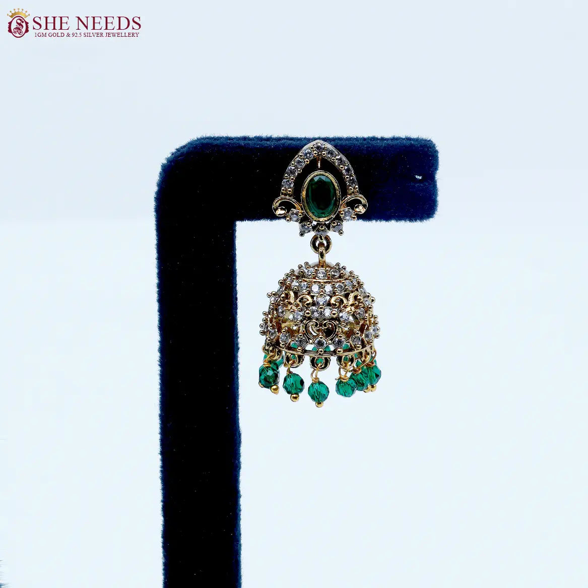 Royal Stone Antique Emerald Green Jhumka Earrings featuring sparkling American Diamonds, antique gold detailing, emerald green stone, and green crystal bead drops.|She Needs Jewellery