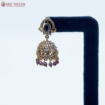 Royal Stone Antique Purple Jhumka Earrings featuring sparkling American Diamonds, antique gold detailing, purple stone centerpiece, and purple crystal bead drops.|She Needs Jewellery

