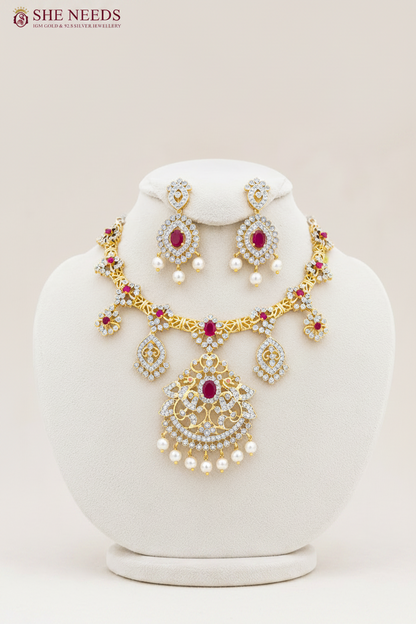 Elegant ruby pink AD stone bridal necklace set with pearl drop earrings in premium gold finish displayed on white mannequin.
