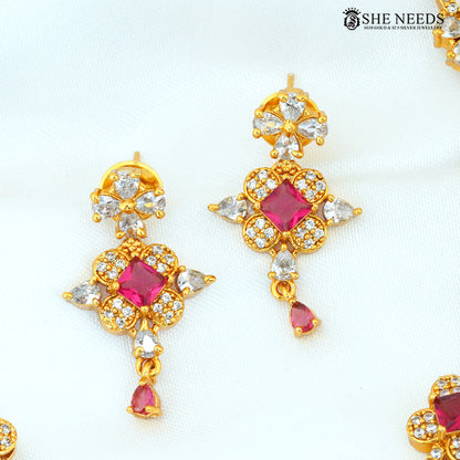Close-up of ruby stone floral gold-plated earrings with sparkling white AD stones and dangling ruby accents|She Needs Jewellery
