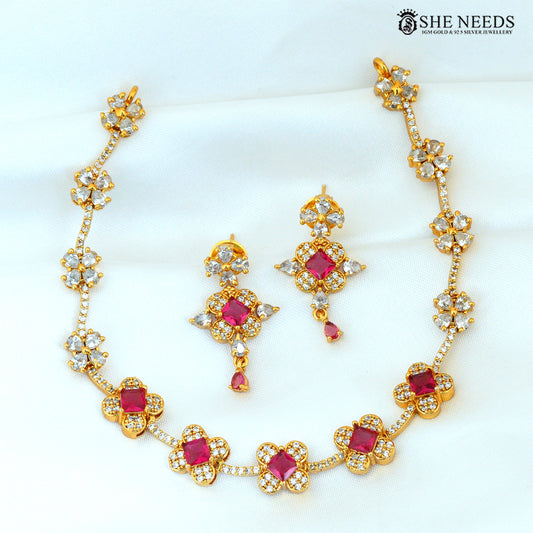 Ruby stone floral gold-plated necklace with matching earrings arranged on a white background|She Needs Jewellery

