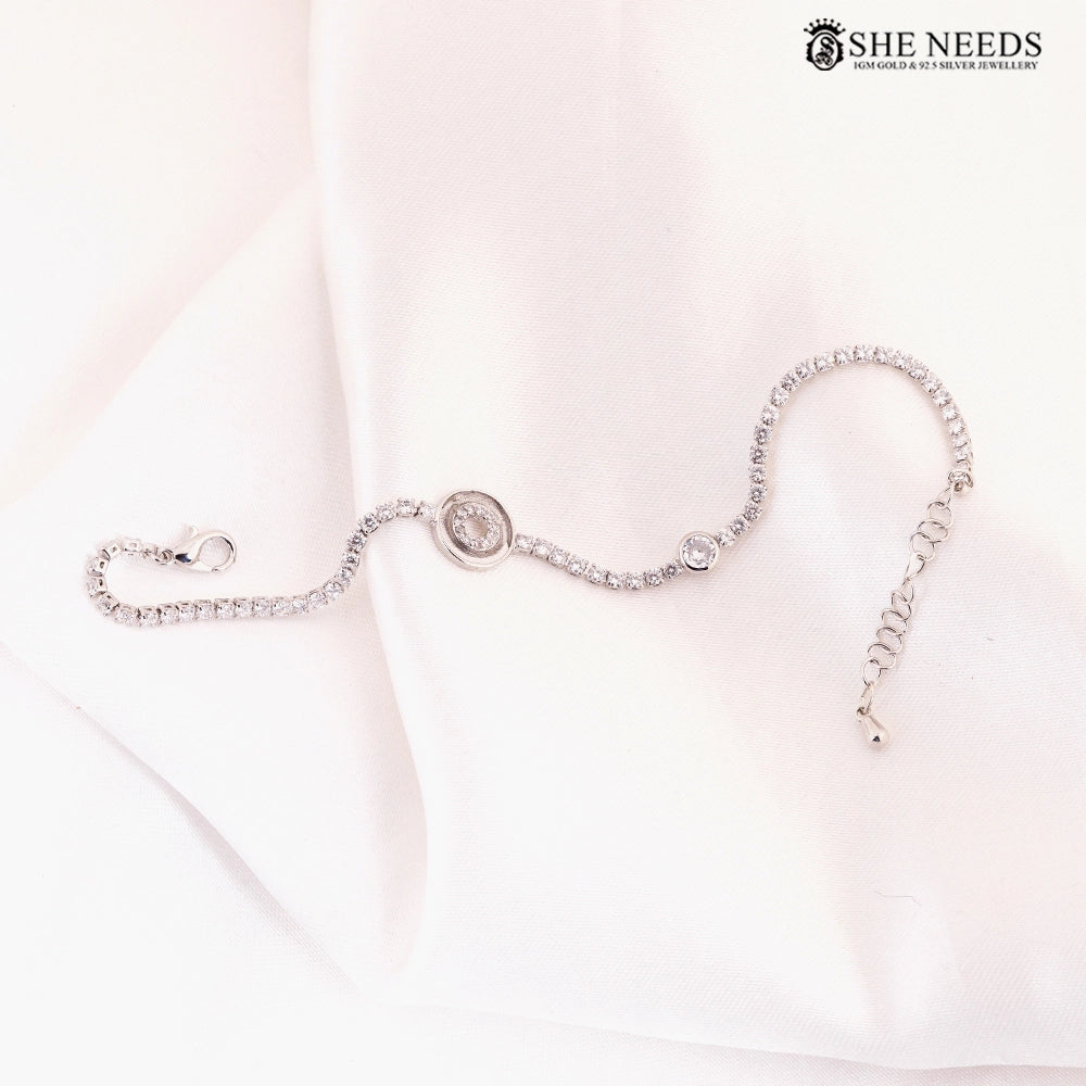 Silver CZ wave bracelet featuring sparkling cubic zirconia stones, a circular crystal centerpiece, and an adjustable extension chain displayed on a white fabric background. |She Needs Jewellery
